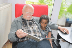 Opa-and-grand-daughter-enjoying-a-great-book-300x200